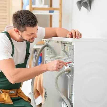 Technician checking the rear hose connections of a household appliance