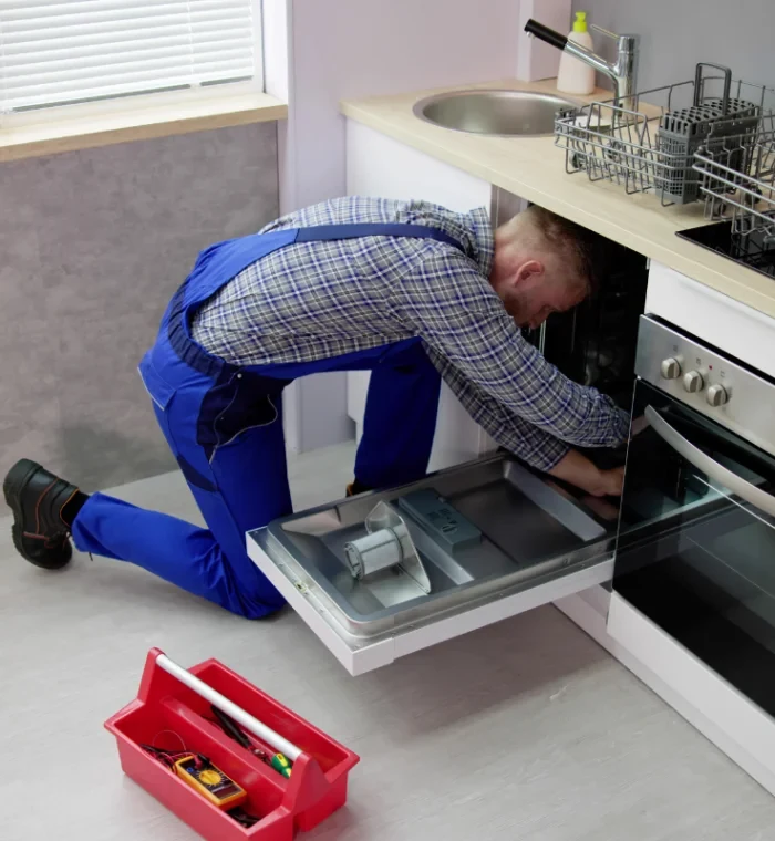 Technician servicing a dishwasher in a residential kitchen