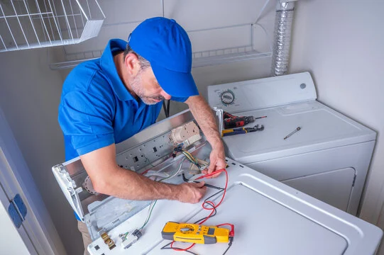 Technician testing laundry appliance controls beside a vented dryer